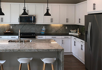 Modern white kitchen renovation in San Gabriel with marble island and black pendant lights